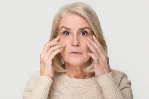 Пожилая женщина смотрит в камеру и беспокоится о морщинах на лице. — стоковое фото