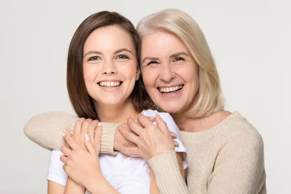 Feliz vieja madre abrazando hija joven aislada en el fondo — Foto de Stock