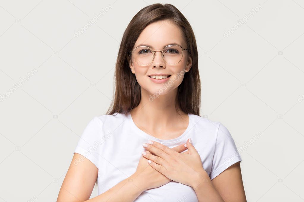 Grateful young woman holding hands on chest isolated on background