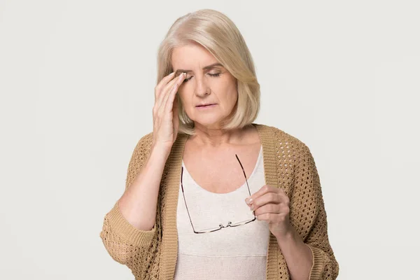 Unavená žena drží brýle pocit očí izolovaný na pozadí — Stock fotografie