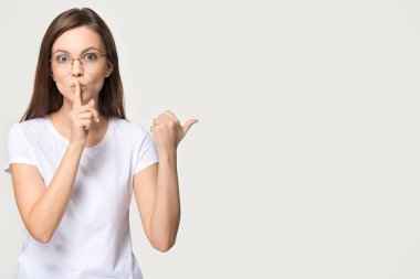 Gri arka plan üzerinde izole dudaklarında parmak tutan sessiz kız