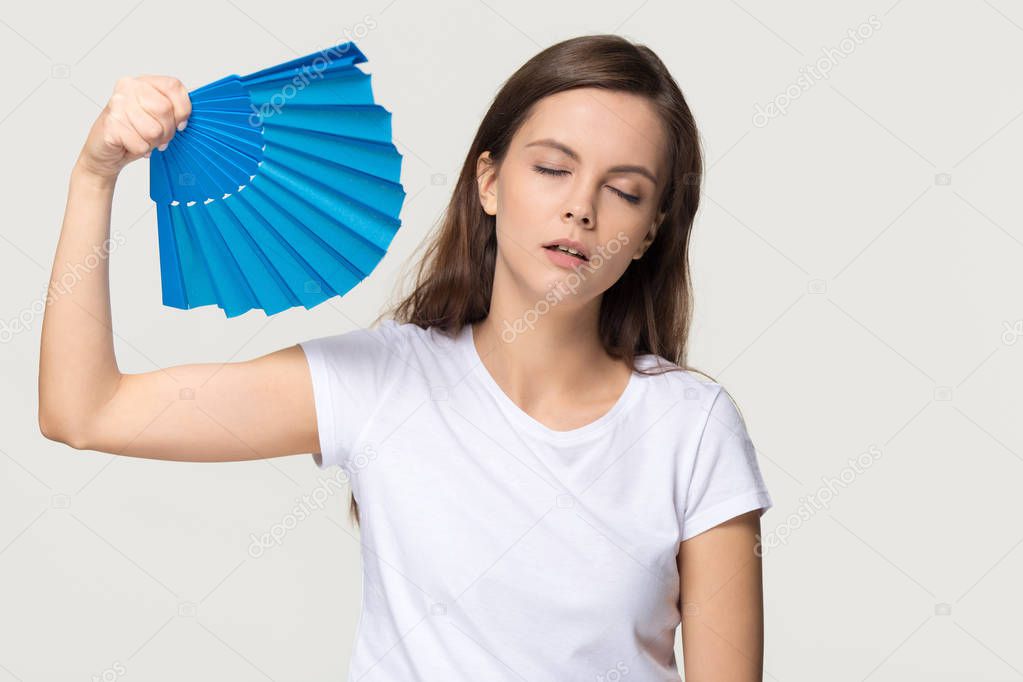 Tired young woman feel overheated suffering from heat waving fan