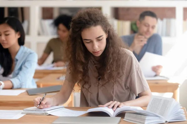 Adolescent fille étudiant avec manuel écriture essai apprentissage dans salle de classe — Photo