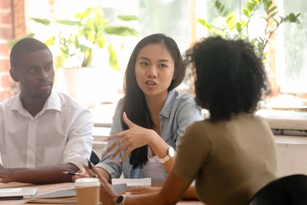 Asiatiska kvinnlig arbetstagare talar träffande åsikt talar till afrikanska kollegor — Stockfoto