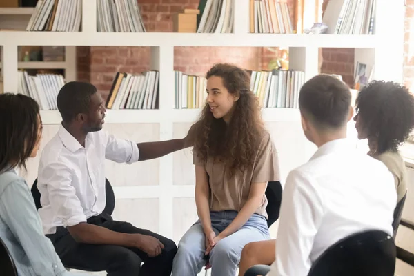 African man psychologist friend supporting caucasian woman sit in circle