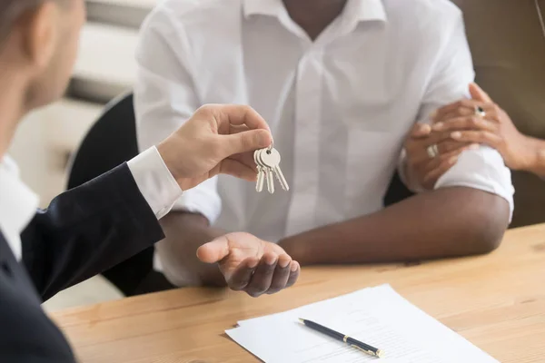 Fastighetsmäklare fastighetsmäklare holding ger nycklar till svart par — Stockfoto