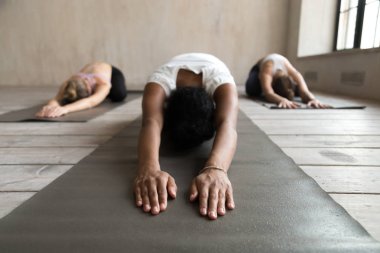 Siyah yogi kadın ve grup Balasana egzersiz yaparak insan