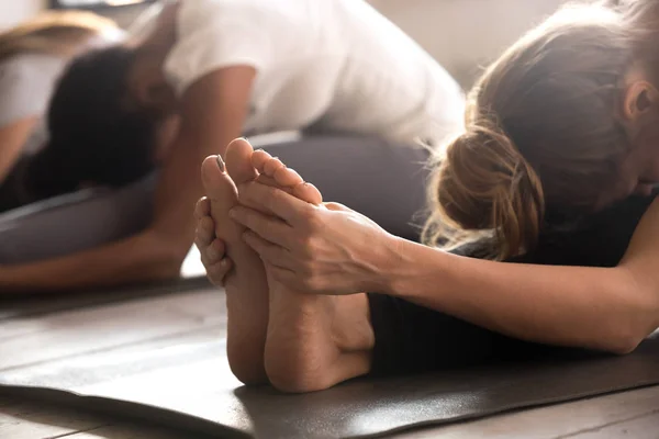 Grupo de mulheres praticando aula de ioga, postura paschimottanasana de perto — Fotografia de Stock