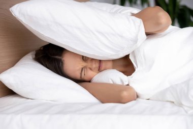 Gürültüden acı yastık, kulaklarıyla kapsayan rahatsız genç kadın