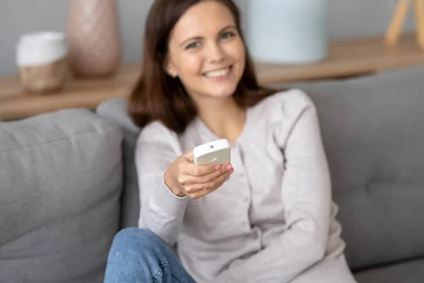 Souriant jeune femme opérant avec climatiseur à la maison — Photo