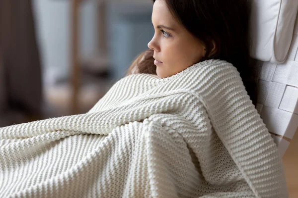 Attractive young woman relaxing under soft blanket in comfortable chair — Stock Photo, Image