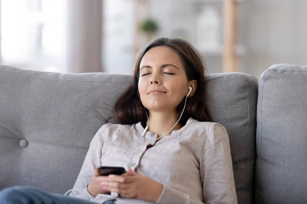 Wanita muda yang damai dengan earphone menikmati musik di rumah — Stok Foto