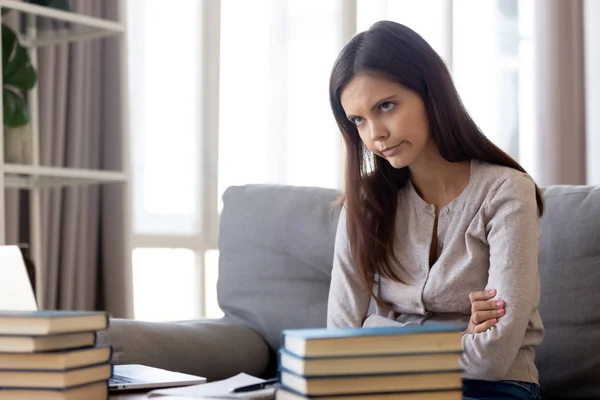 Нещасна жінка навчається вдома, ноутбук і стопка книг на столі — стокове фото
