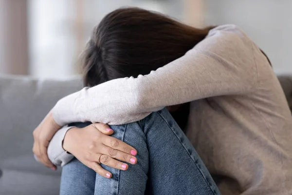 Jeune femme bouleversée embrassant les genoux, pleurant, se sentant malheureuse — Photo