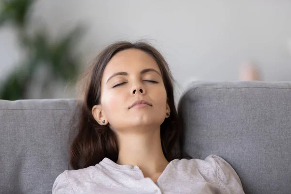 Rustige jonge vrouw ontspannen op comfortabele sofa met gesloten ogen dicht omhoog — Stockfoto