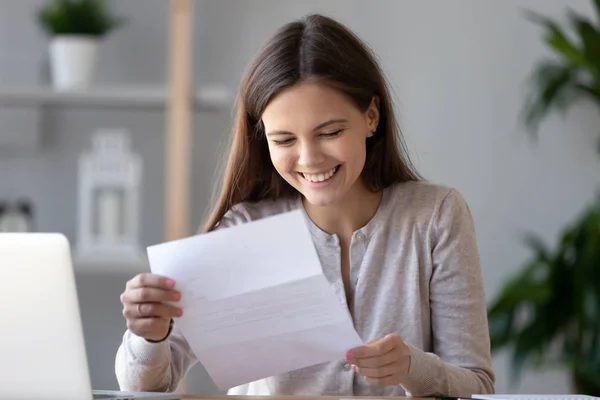 Sourire étudiante heureuse ou travailleuse lisant de bonnes nouvelles dans une lettre papier — Photo