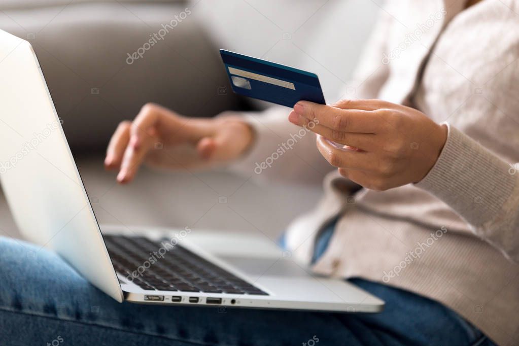 Close up woman shopping, paying by credit card online, using laptop