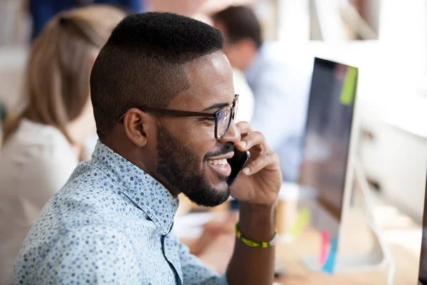 Smiling african employee talking on phone with client