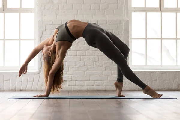 Hermosa mujer practicando yoga, de pie en pose Cosa Salvaje, Camatkarasana — Foto de Stock