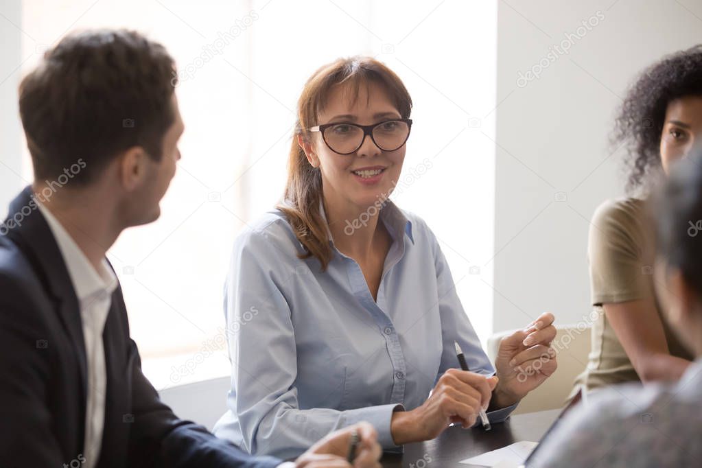 Middle-aged businesswoman mentor coach speaks at group office conference meeting