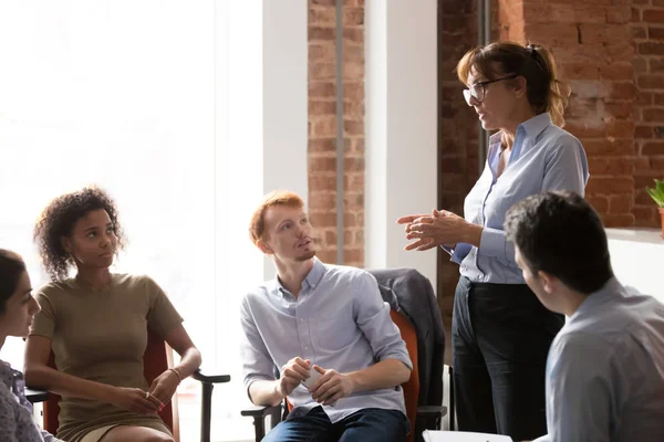 Líder de entrenador serio que habla enseñando a personal diverso en reunión de grupo — Foto de Stock