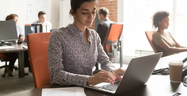 Joven empleada india de negocios usando portátil en el lugar de trabajo en la oficina — Foto de Stock