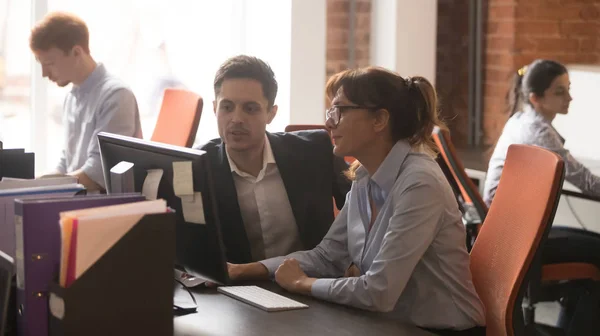 Los colegas serios que trabajan juntos en la oficina moderna hablan usando la computadora — Foto de Stock