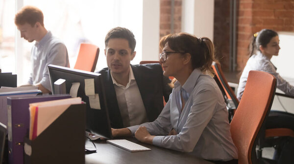 Serious colleagues working together in modern office talking using computer