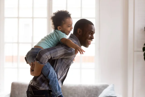 Heureux petit gosse équitation noir papa avoir amusant à la maison — Photo