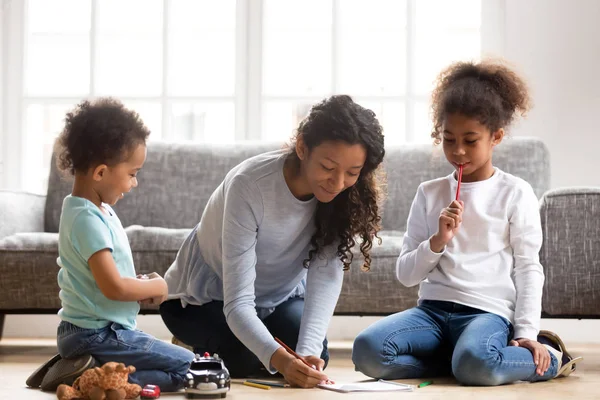 Jeune maman dessinant ensemble avec de petits enfants métis — Photo