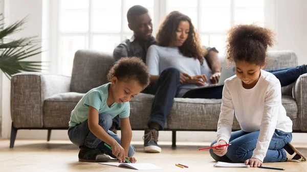 Niños pintando en libros de color relajándose con sus padres en casa — Foto de Stock