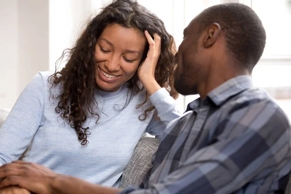 Happy black couple relax on couch talking holding hands — Stock Photo, Image