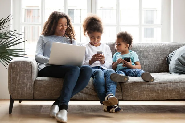 Jovem família negra sentar no sofá usando gadgets — Fotografia de Stock