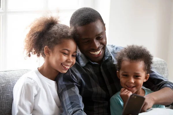 Joyeux papa noir jouer sur smartphone avec des petites filles — Photo