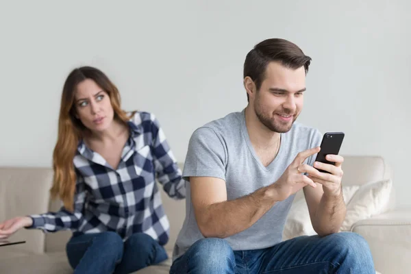 Jealous suspicious wife arguing with obsessed husband holding phone