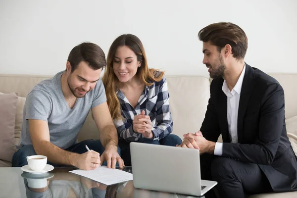 Happy couple renters or tenants sign rental contract meeting realtor