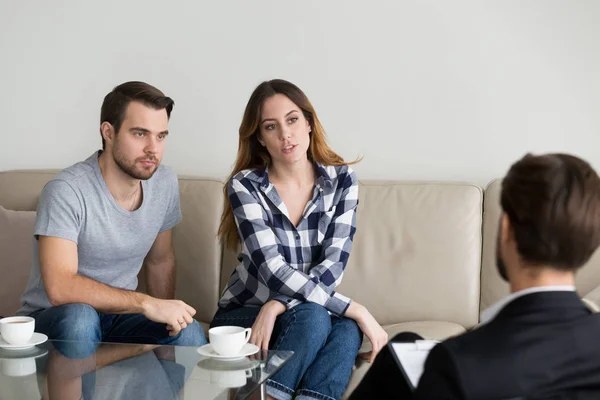 Infeliz pareja milenaria hablando con el psicólogo sentado en el sofá — Foto de Stock