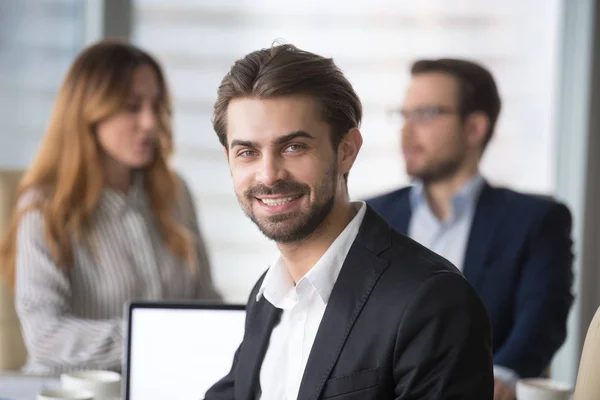 Empresário sorridente de terno olhando para câmera posando na reunião — Fotografia de Stock