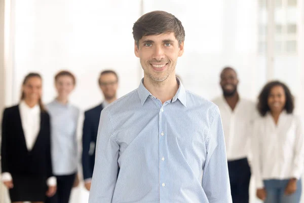 Sorrindo empregado masculino de pé no escritório olhando para a câmera — Fotografia de Stock