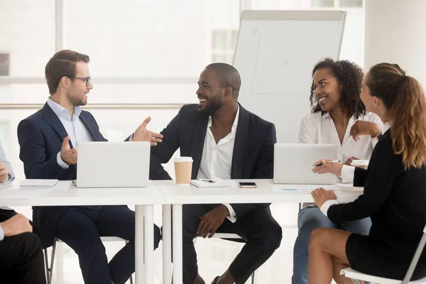 Teamleider van de multiraciale werknemers achter bestuurskamer bureau luisteren — Stockfoto