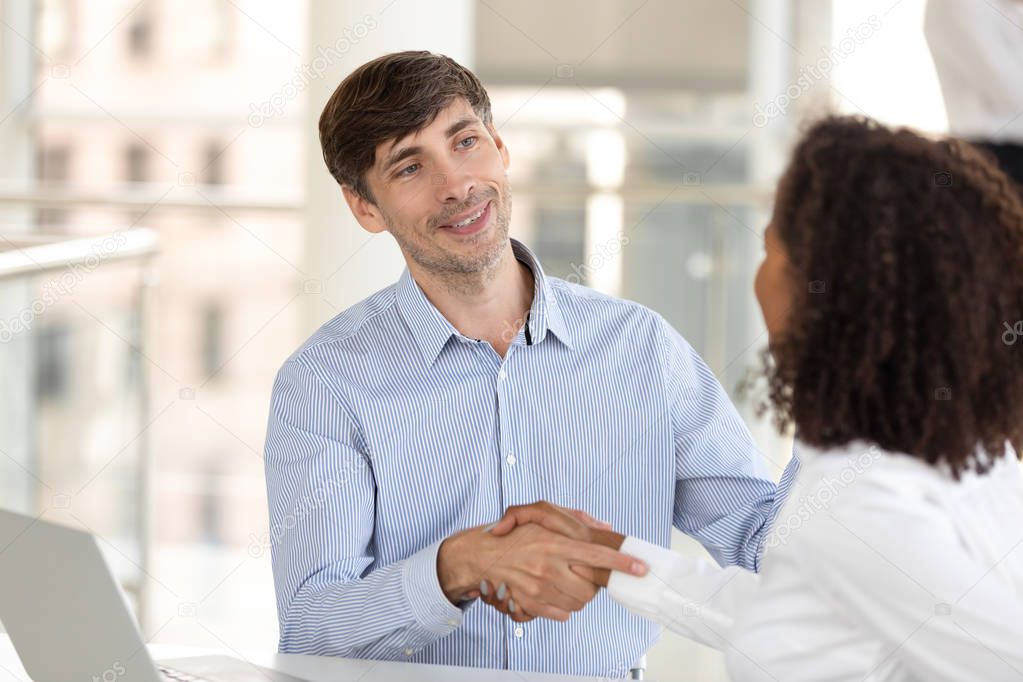 Diverse business partners shake hands after successful negotiations in office