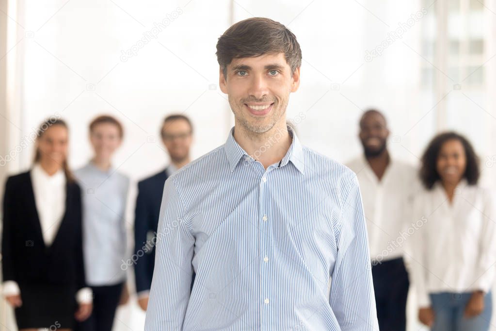 Smiling male employee standing in office looking at camera