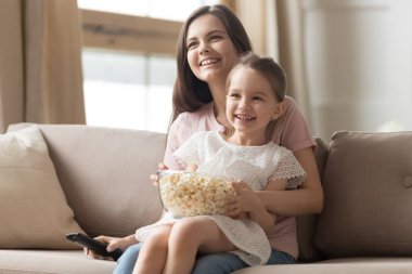 Mutlu anne ve çocuk kız kanepede televizyon izlerken gülmekten