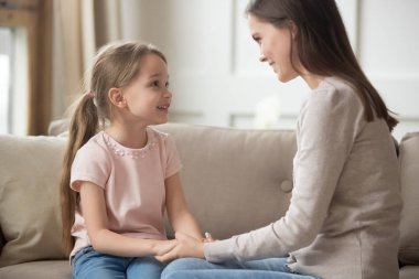 Sevgi dolu bir anne ve çocuk tutuşup koltukta oturan konuşuyor