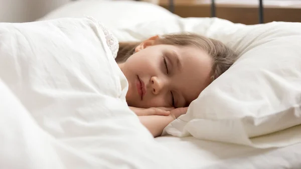 Calma niña durmiendo en la cama cubierta con edredón caliente — Foto de Stock