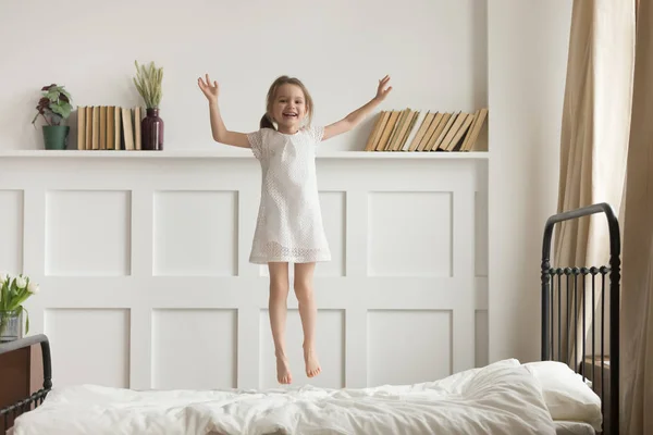 Happy funny child girl jumping on bed alone feeling joy — Stok Foto