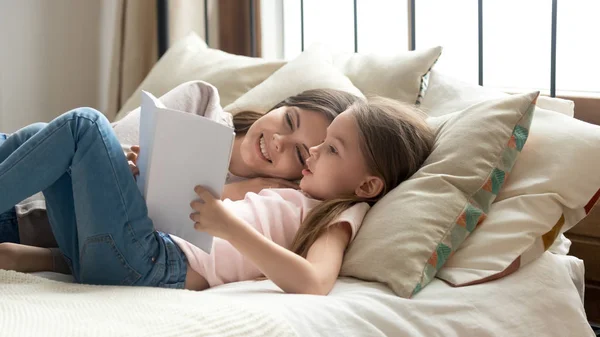 Mignon enfant fille tenant livre lecture à maman au lit — Photo