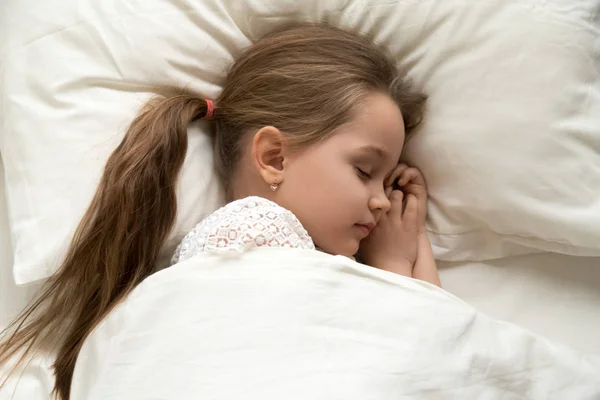 Linda niña tranquila durmiendo acostada en una cama cómoda — Foto de Stock