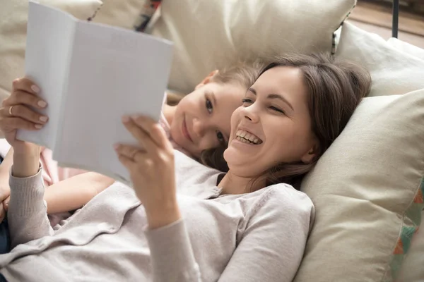Щаслива мати і дочка читають книгу сміється в ліжку — стокове фото