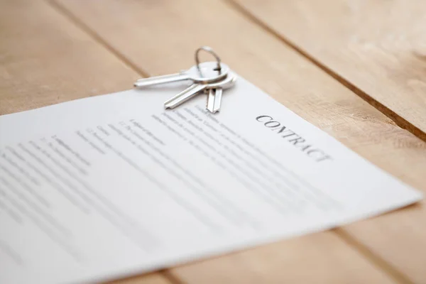 Keys and contract paper on a wooden table — Stock Photo, Image